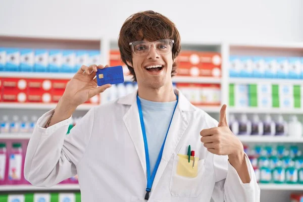 Jovem Hispânico Trabalhando Farmácia Farmácia Farmácia Segurando Cartão Crédito Sorrindo — Fotografia de Stock