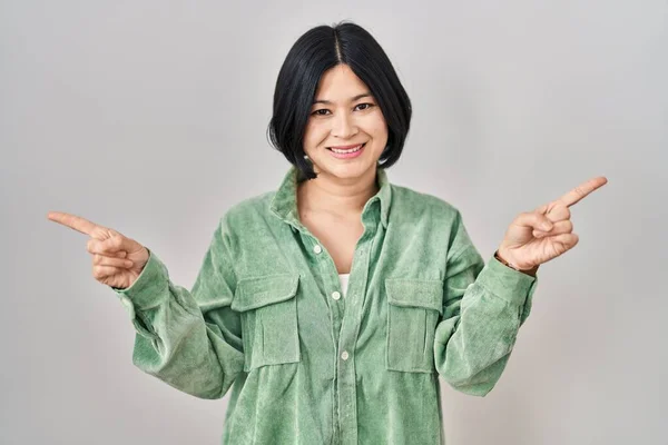 Ung Asiatisk Kvinna Står Över Vit Bakgrund Leende Säker Pekar — Stockfoto