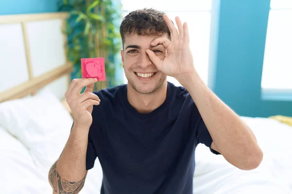 Mladý Hispánec Sedí Posteli Drží Kondom Šťastně Usmívá — Stock fotografie