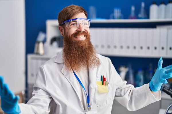 Young redhead man scientist smiling confident speaking at laboratory