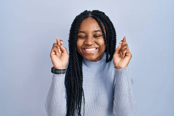 African American Woman Standing Blue Background Gesturing Finger Crossed Smiling — Stock Photo, Image