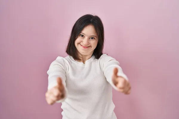 ダウン症の女性はピンクの背景の上に立って手で積極的なジェスチャーを行うことを承認し 親指を笑顔と成功のために幸せ 勝者のジェスチャー — ストック写真