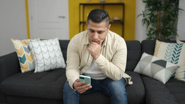 Junger Hispanischer Mann Sitzt Mit Smartphone Auf Dem Sofa Und — Stockfoto