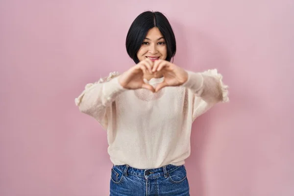 Young Asian Woman Standing Pink Background Smiling Love Doing Heart — Stock fotografie