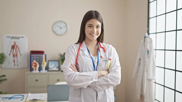 年轻美丽的惊慌失措的女医生微笑着 自信地站在诊所里 双手交叉地微笑着 — 图库照片