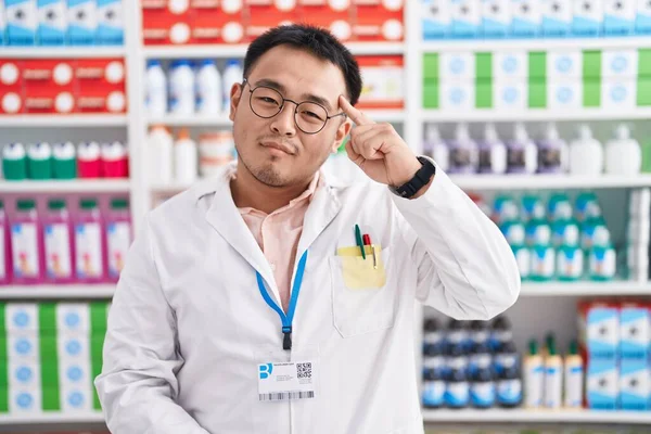 中国の若い男は薬局で働いているドラッグストア1本の指で頭を指して笑顔 素晴らしいアイデアや考え 良い記憶 — ストック写真