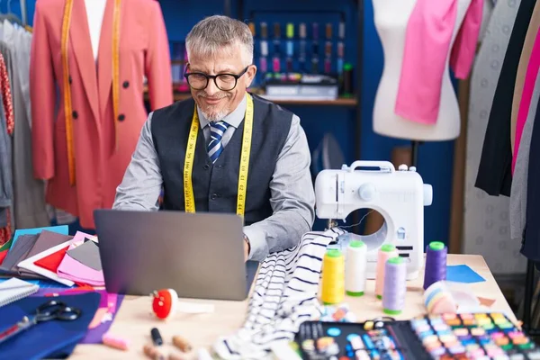 stock image Middle age grey-haired man tailor smiling confident using laptop at clothing factory