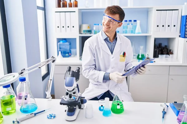 Young Man Scientist Smiling Confident Reading Report Laboratory — Stock Photo, Image