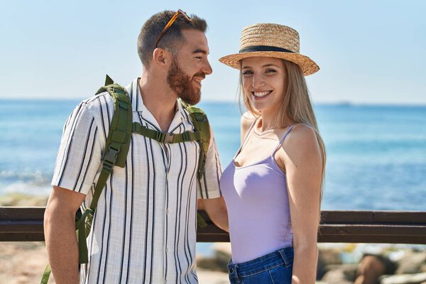 Man and woman tourist couple smiling confident hugging each other at seaside