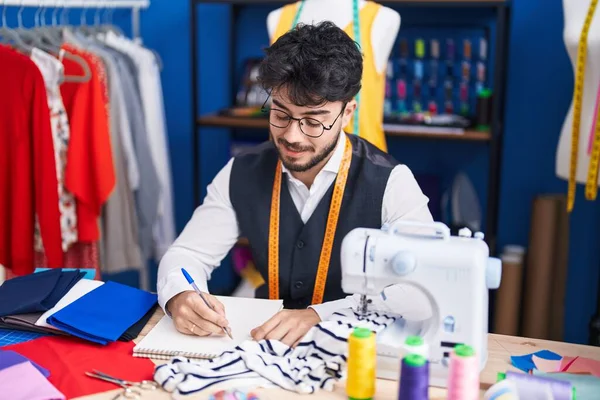 Young Hispanic Man Tailor Smiling Confident Drawing Notebook Sewing Studio — Stockfoto