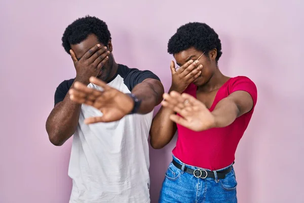 Młoda Afrykańska Para Stojąca Nad Różowym Tłem Zakrywająca Dłońmi Oczy — Zdjęcie stockowe
