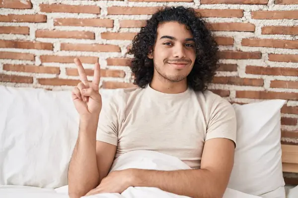 Genç Latin Adam Yatakta Oturmuş Zafer Jesti Yapıyor — Stok fotoğraf