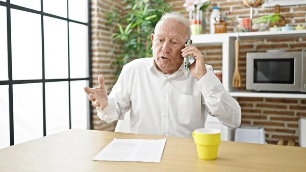 Senior Hombre Pelo Gris Enojado Discutiendo Teléfono Inteligente Sentado Mesa —  Fotos de Stock