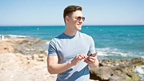 Νεαρός Ισπανόφωνος Τουρίστας Χαμογελώντας Αυτοπεποίθηση Χρησιμοποιώντας Smartphone Στην Παραλία — Φωτογραφία Αρχείου