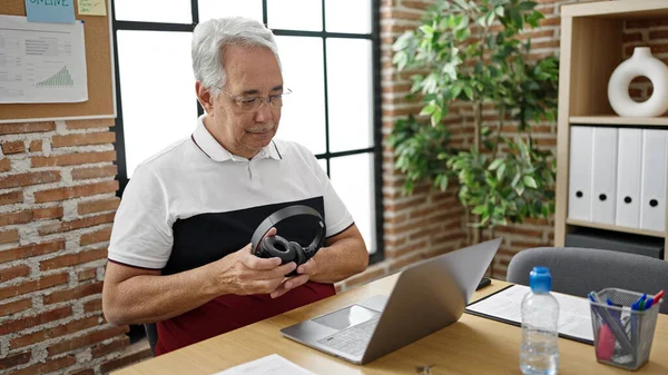 オフィスでヘッドフォンを置くラップトップを使用してグレーの髪のビジネスワーカーを持つ中世の男 — ストック写真