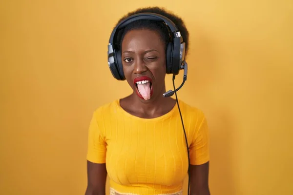 Afrikaanse Vrouw Met Krullend Haar Staande Gele Achtergrond Met Koptelefoon — Stockfoto