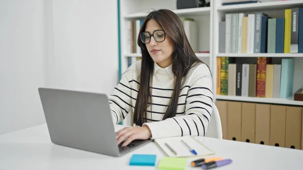 Young Beautiful Hispanic Woman Student Using Laptop Serious Expression Library — Stock Photo, Image