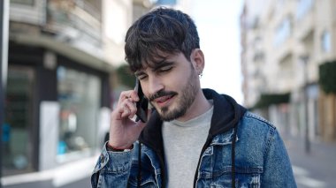 Genç İspanyol adam caddede telefonla konuşuyor.