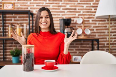 Genç İspanyol kadın evde kahve içiyor zaferi mutlu bir gülümsemeyle kutluyor ve kazanan el kaldırarak ifade ediyor. 