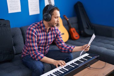 Young man musician playing piano keyboard at music studio