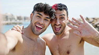 Two men tourist couple smiling confident having video call at beach clipart