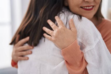 Two women mother and daughter smiling confident hugging each other at home