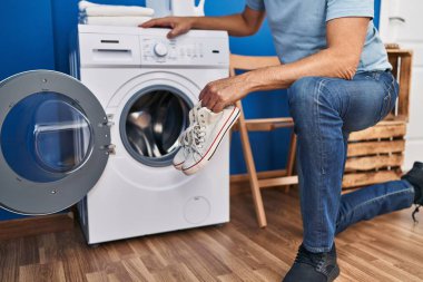 Middle age man washing sneakers at laundry room