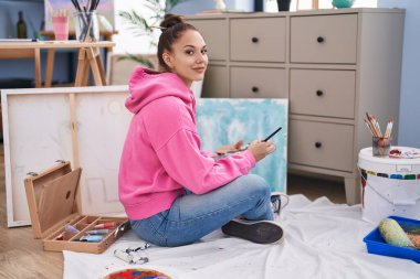 Young woman artist sitting on floor drawing at art studio