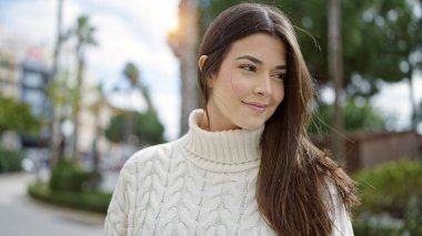 Young beautiful hispanic woman smiling confident looking to the side at street