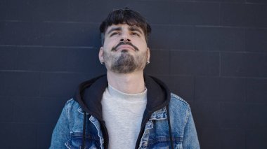 Soyutlanmış siyah arka planda ciddi bir ifadeyle duran İspanyol genç adam.