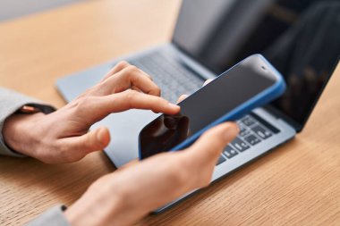 Ofiste dizüstü bilgisayar ve akıllı telefon kullanan beyaz bir kadın.