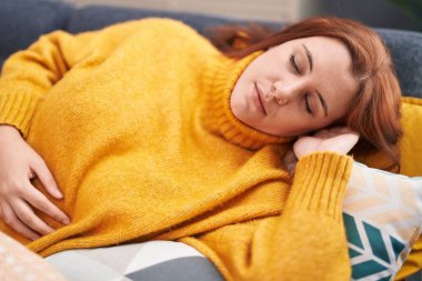 Young beautiful plus size woman lying on sofa sleeping at home