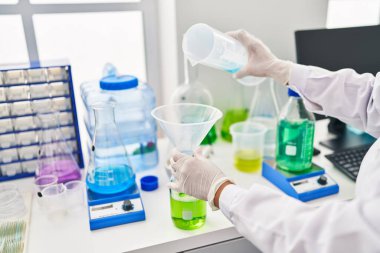 Middle age hispanic woman wearing scientist measuring liquid at laboratory
