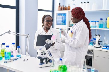 African american women scientist holding test tube writing on document at laboratory
