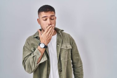Tecrit edilmiş arka planda duran genç İspanyol adam, ağzını eliyle kapatmaktan sıkılmış. Huzursuz ve uykulu.. 