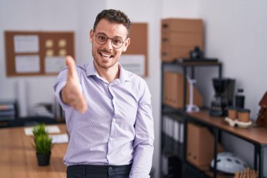 Ofisteki genç İspanyol adam selamlamak ve karşılamak için dostça el sıkışarak gülümsüyor. başarılı iş. 