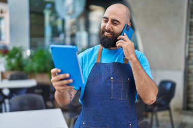 Genç, kel adam, garson, dokunmatik telefon, kahve dükkanının terasında.