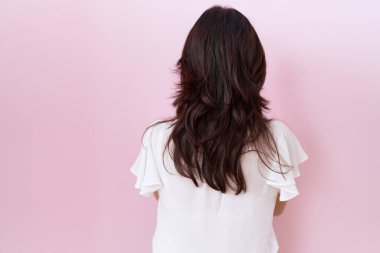 Orta yaşlı, beyaz tişört ve gözlüklü İspanyol bir kadın ters dönüp kollarını kavuşturmuş bakıyor. 