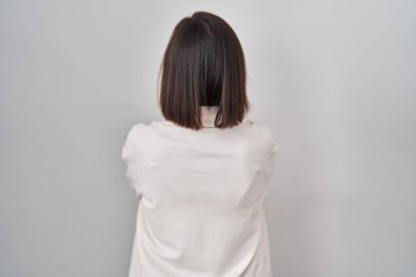 Orta yaşlı İspanyol bir kadın izole edilmiş arka planda dikilip kollarını kavuşturup arkasına bakıyor. 