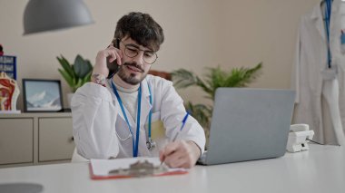 Genç İspanyol doktor klinikte telefonla konuşuyor.