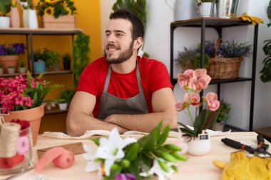 Çiçekçi dükkanında çalışan genç İspanyol bir adam profilini rahatlatmak için doğal bir yüz ve kendine güvenen bir gülümsemeyle poz veriyor.. 