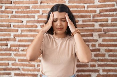 Duvarın başında eli başının üstünde duran İspanyol bir kadın. Stres yüzünden baş ağrısı çekiyor. migren ağrısı. 