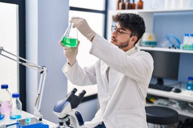 Genç İspanyol bilim adamı laboratuvarda sıvıyı ölçüyor.