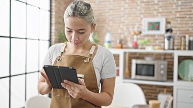 Yemek odasında dokunmatik ped kullanan önlük giyen güzel İspanyol bir kadın.