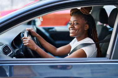 African american woman smiling confident driving car at street