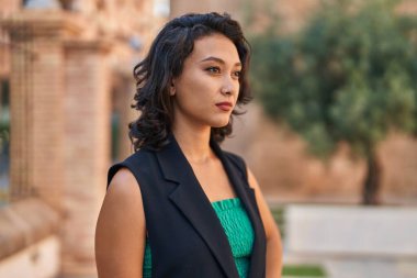 Young beautiful hispanic woman with relaxed expression standing at street