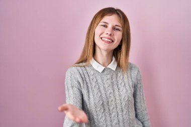 Pembe arka planda duran güzel bir kadın neşeli bir şekilde gülümseyerek avuç içi yardım ve kabullenme teklif ediyor.. 