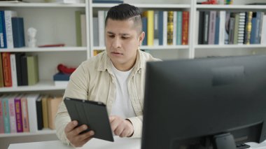 Kütüphane üniversitesinde bilgisayar ve touchpad kullanan genç İspanyol öğrenci.