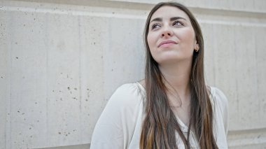 Genç, güzel İspanyol bir kadın, kendinden emin bir şekilde, izole beyaz arka planda, gökyüzüne bakıyor.