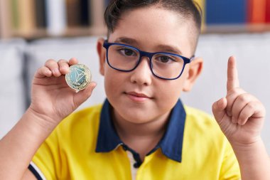 Tron kripto para tutan genç İspanyol çocuk bir fikir veya soruyla gülümsüyor mutlu bir yüzle işaret ederek, bir numara 